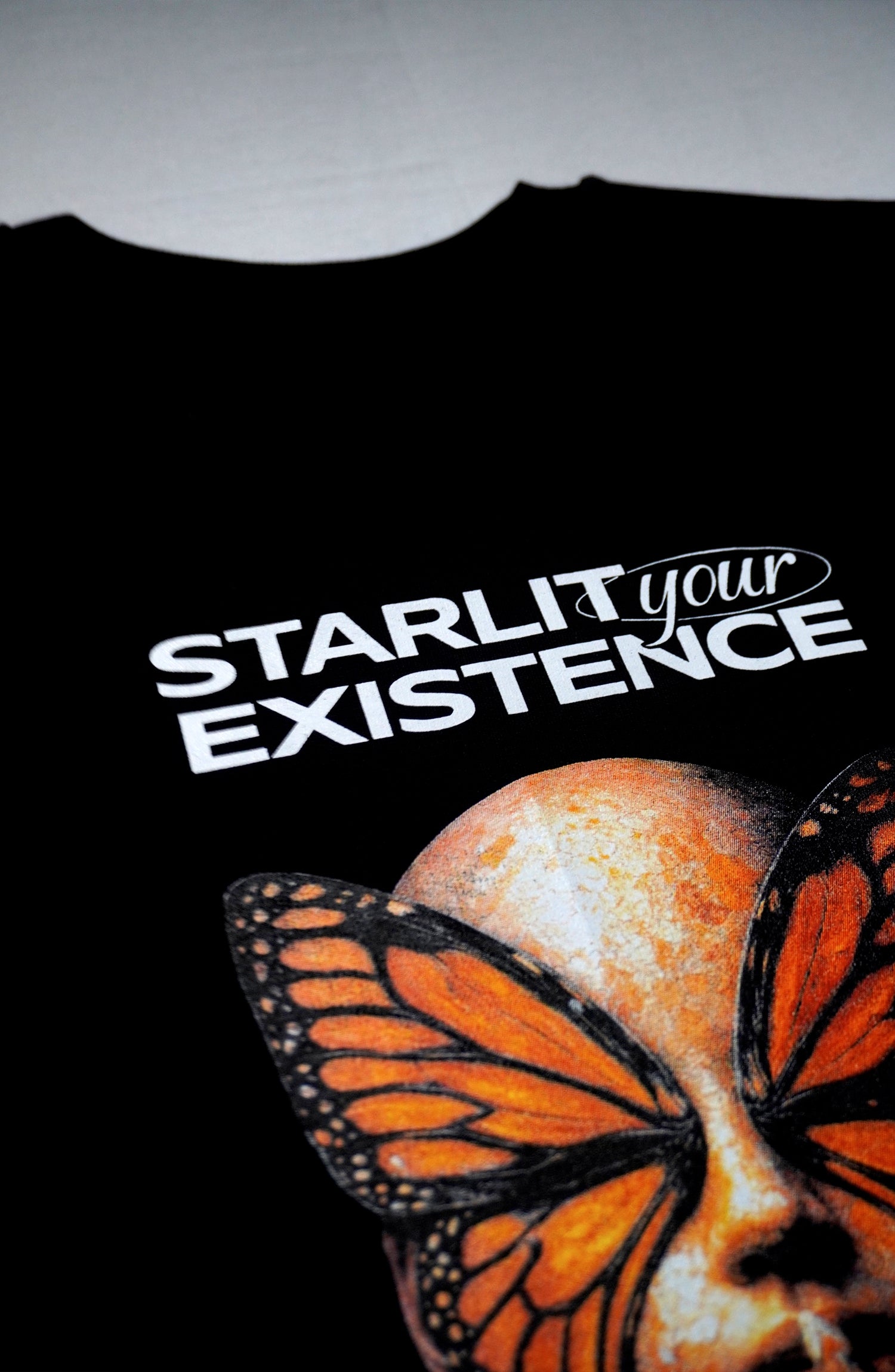 Black t-shirt with a butterfly human and text 'STARLIT your EXISTENCE' on a French terry oversized t-shirt